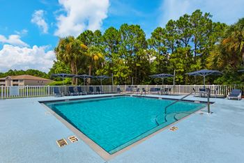 An outdoor pool with seating and umbrellas